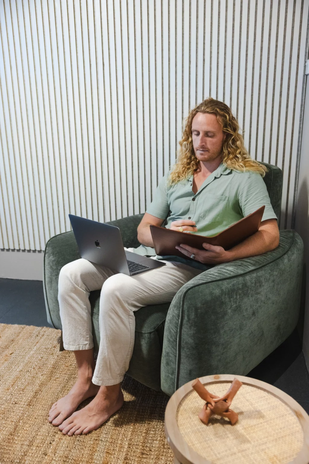 Therapist Riley with a laptop and notes, facilitating online therapy from a comfortable, relaxed setting at Nature Of Wellness, Gold Coast.