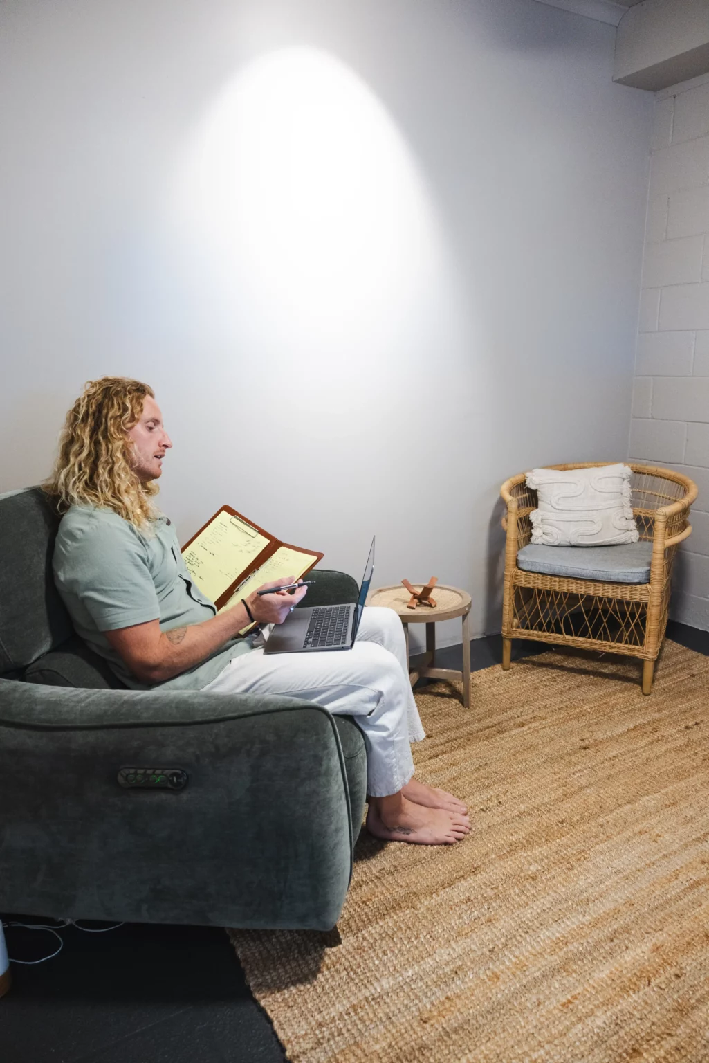 Therapist Riley working on his laptop while taking notes, providing online therapy sessions at Nature Of Wellness, Gold Coast.