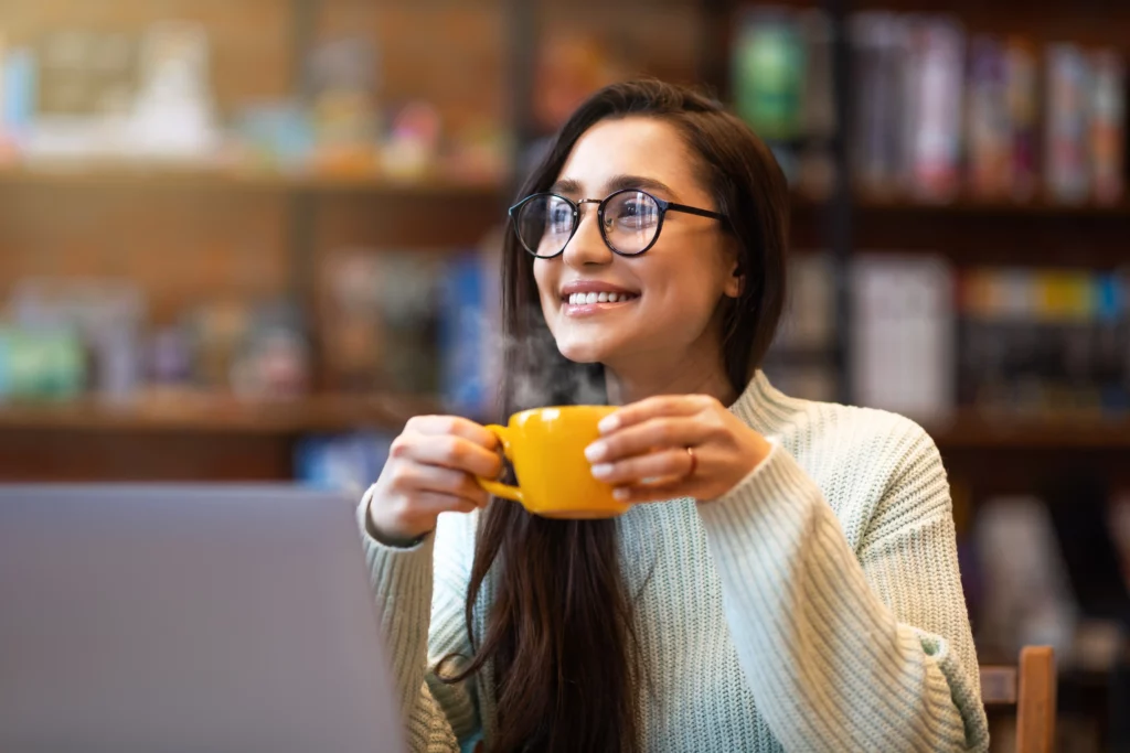 Happy young woman enjoying a coffee break in a cozy workspace